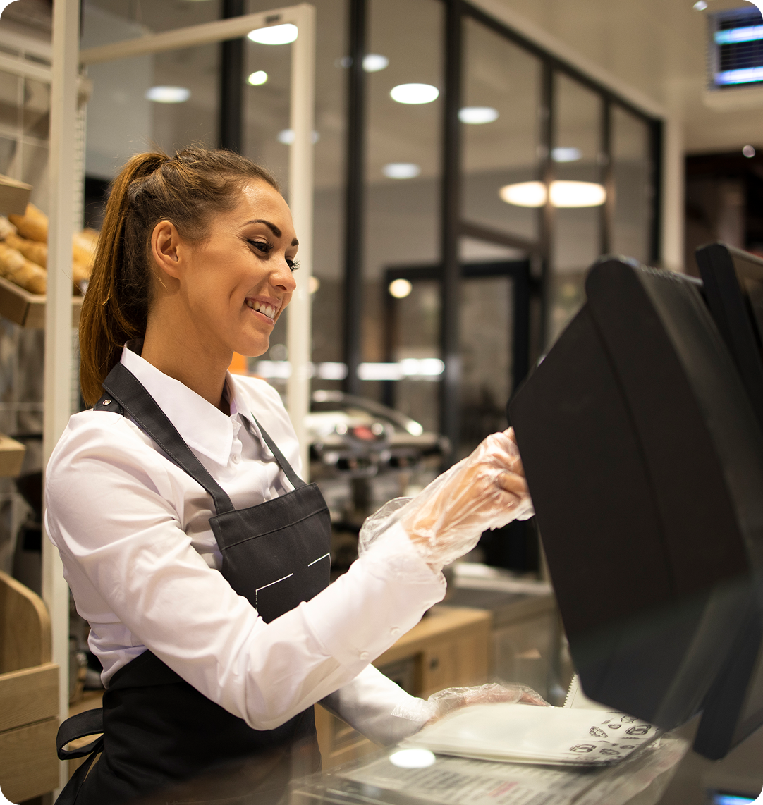 Payment terminal at cafe counter with rows of oat milk cartons in background, terminal displaying payment interface with card being processed